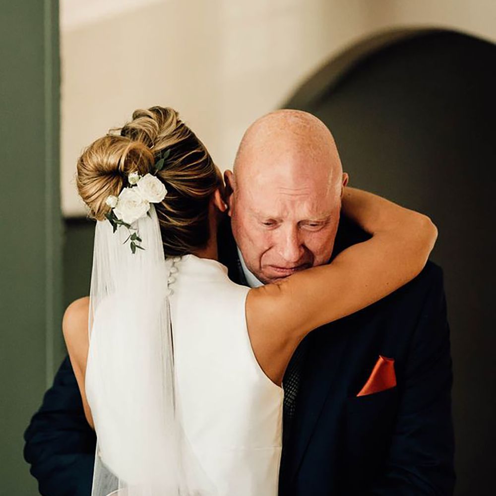 father of the bride embracing bride during first look