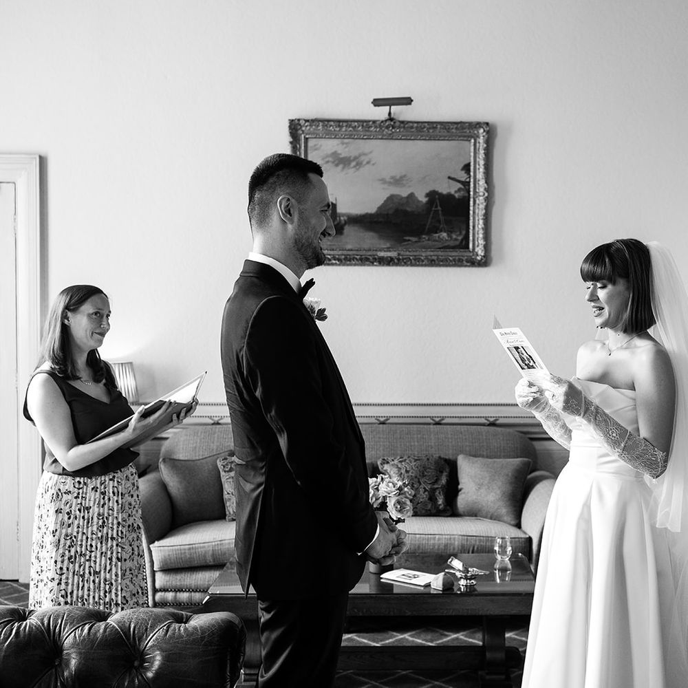 black and white photo of couple practising vows celebrant smiling watching