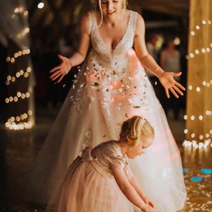Bride in Lace Wedding Dress Throwing Confetti Over Flower Girl