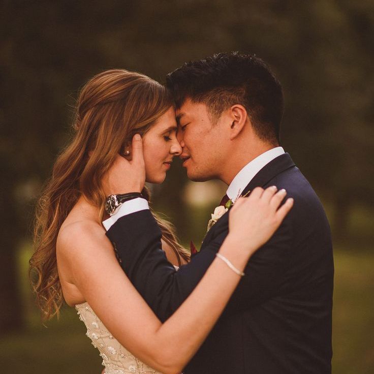 Bride in Pronovias Wedding Dress & Groom in Blue Suit Lean In For A Kiss At Rustic Barn Wedding