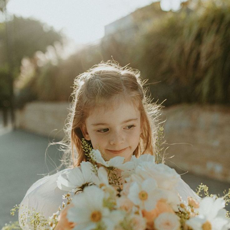 Flower Girl in White Puff Sleeve Dress Holding the Bridal Bouquet with Roses, Cosmos & Daisies