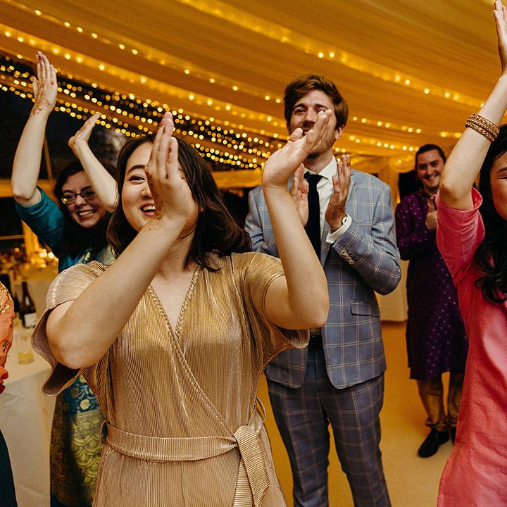 Wedding guests clap and dance at their wedding reception