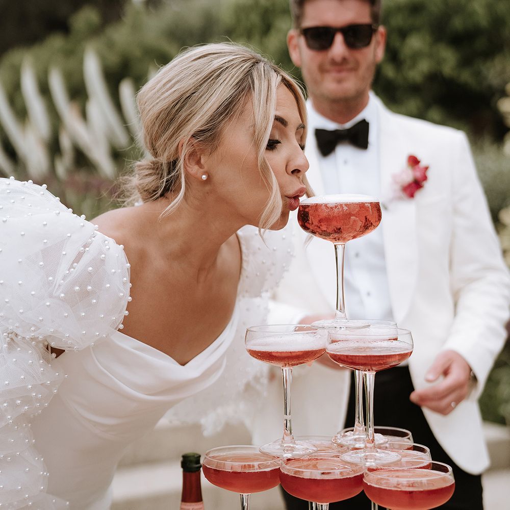 Bride drinks pink champagne from champagne tower