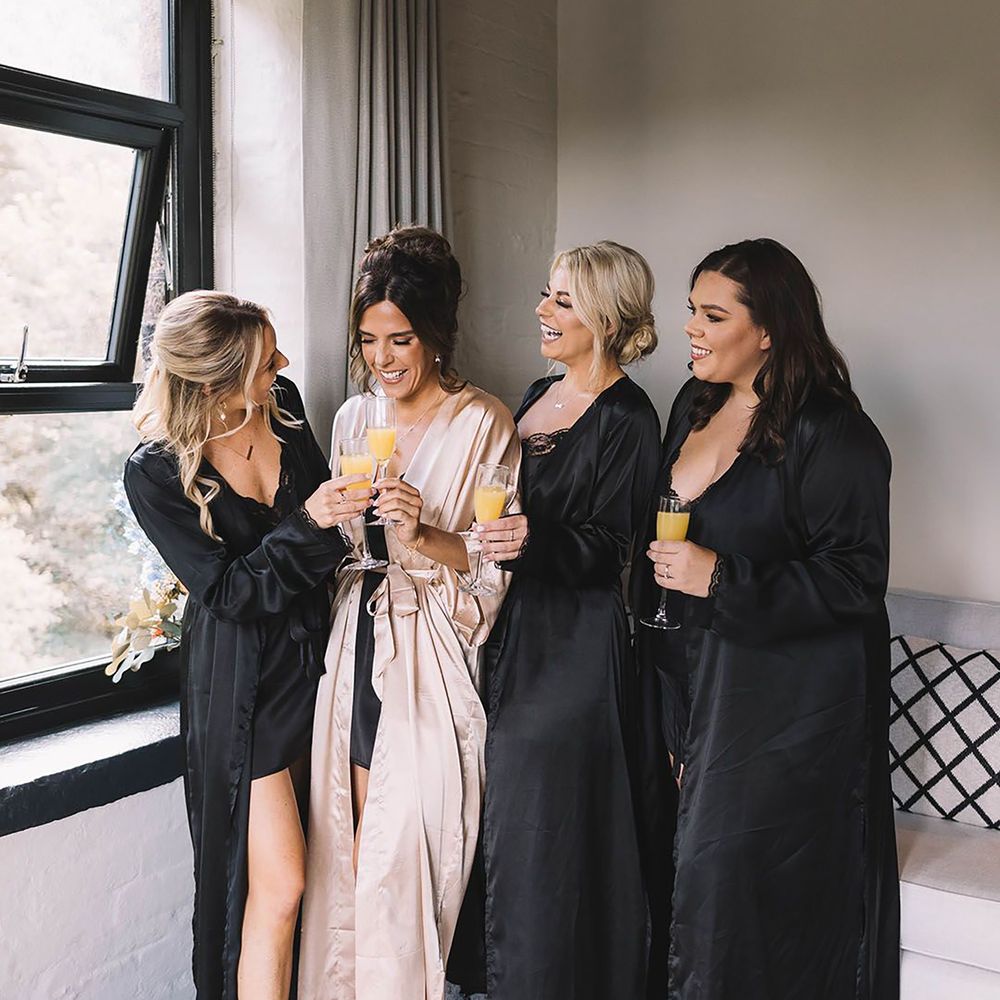 Bridesmaids wearing black satin robes with the bride in a gold robe