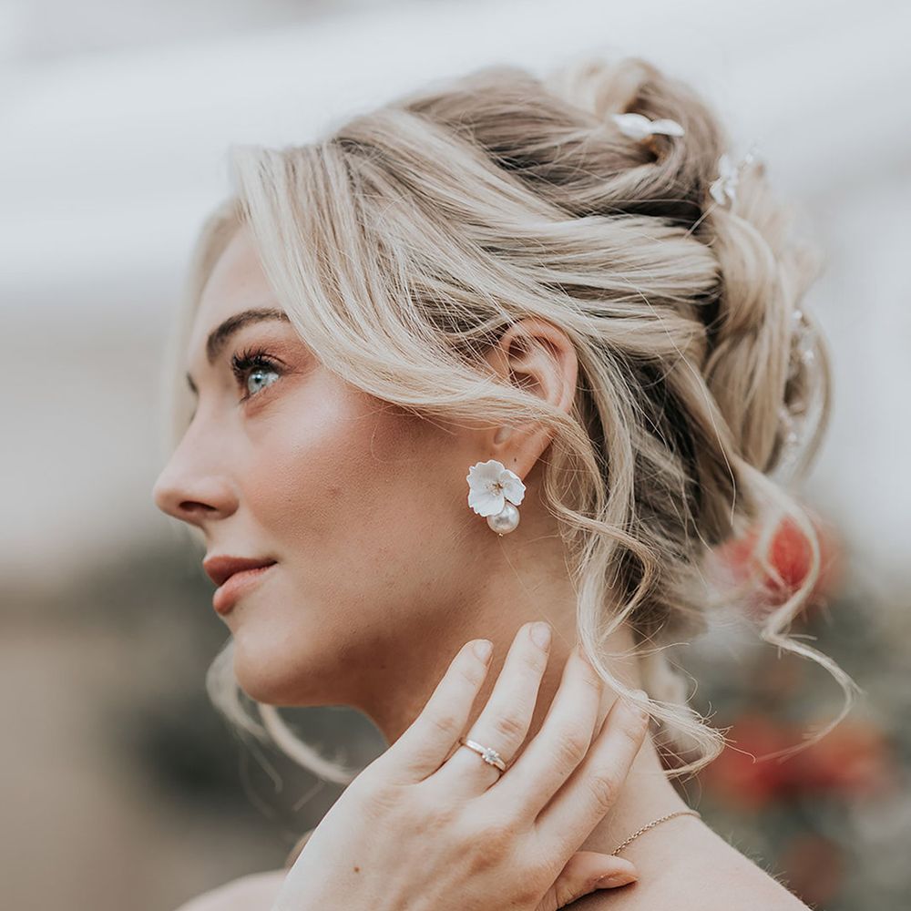 Bride wearing white flower enamel wedding earrings
