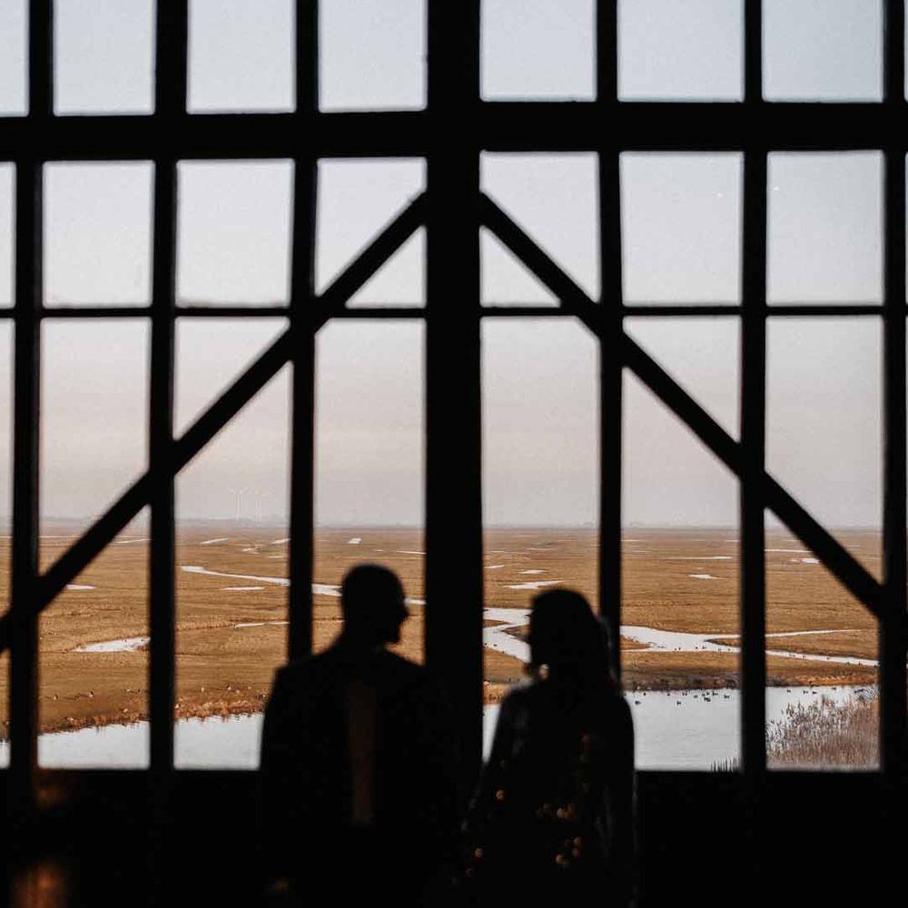 Couple looks out from windows at luxe wedding venue