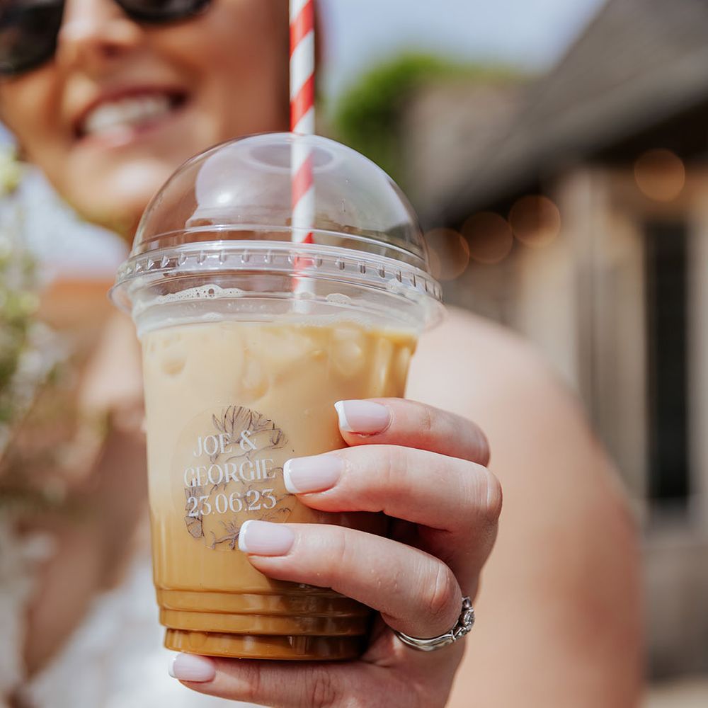 Bride carrying plastic cup of iced coffee