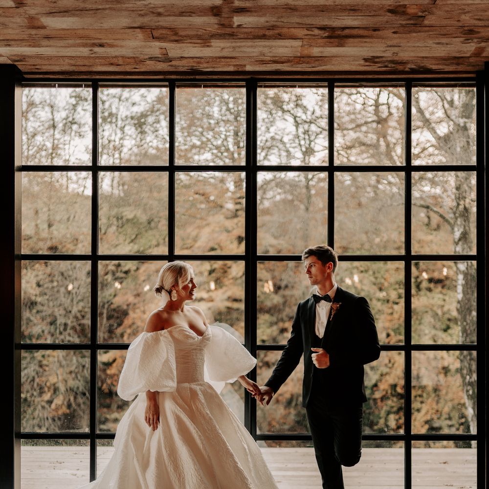 Bride in princess wedding dress with groom in front of floor to ceiling windows