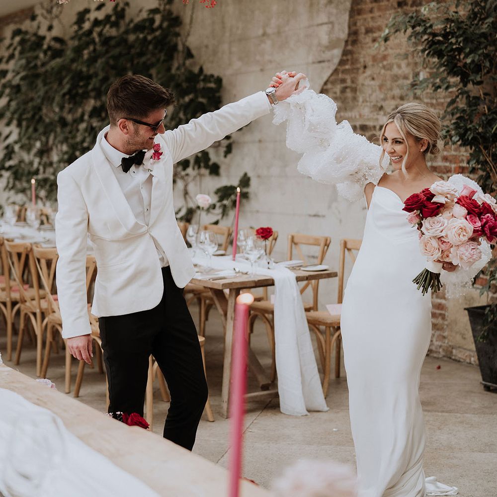 Bride and groom walking around their wedding breakfast with red and pink theme