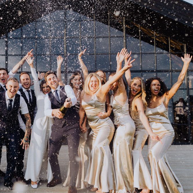 Champagne pop wedding photo with the wedding party