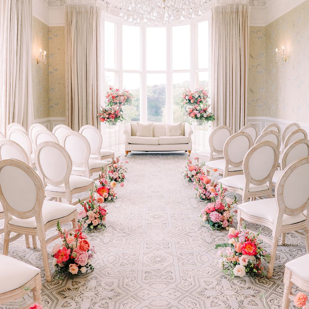 Pink flowers decorate the aisle at country house wedding