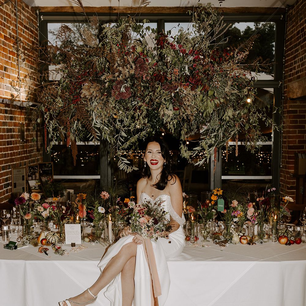 Bride sits on the table at festive winter wedding at Wasing Park