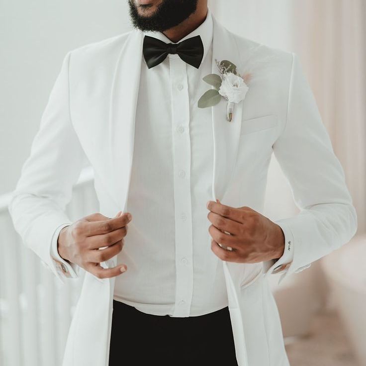 Groom in A White Wedding Suit & Black Bow Tie with a White Flower Buttonhole