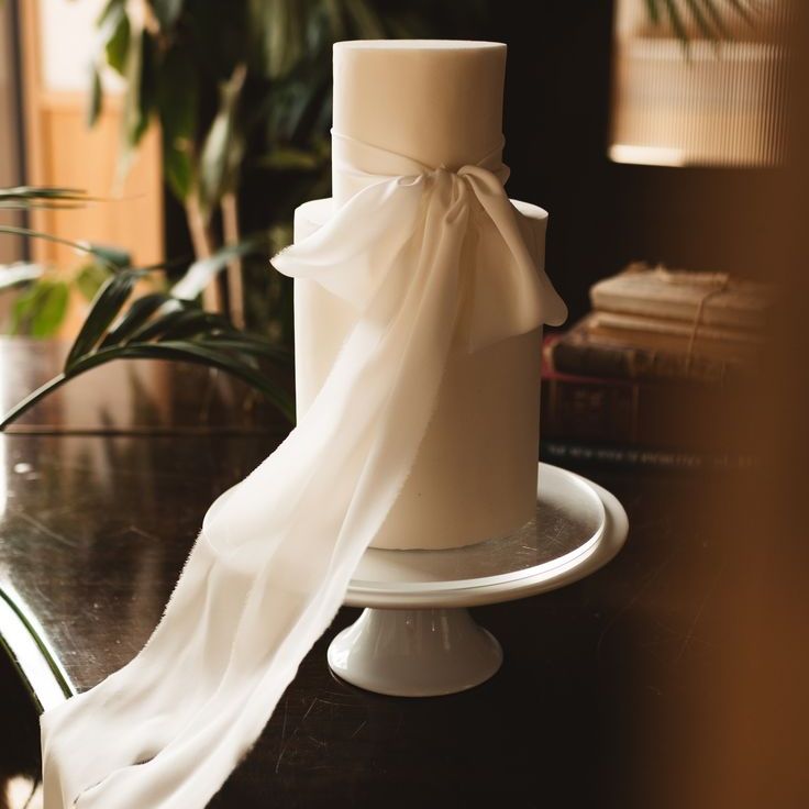 Tall Two Tier White Iced Wedding Cake Decorated with White Satin Bow