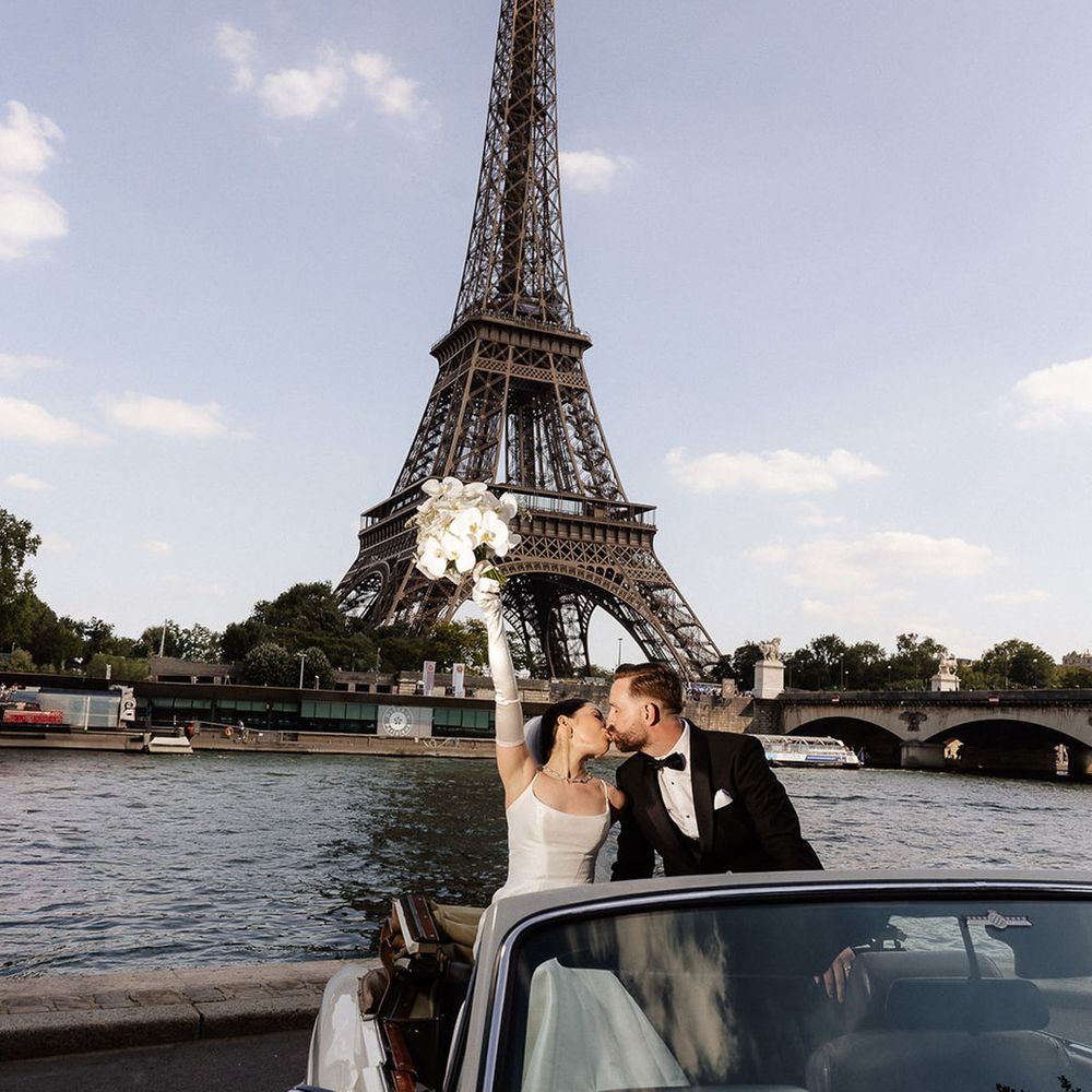 couple-kisses-in-white-wedding-car-in-front-of-eiffel-tower