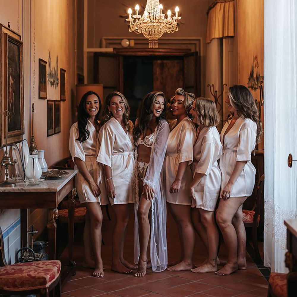 Bridal party in pink satin robes with the bride in white matching lingerie set with sheer robe