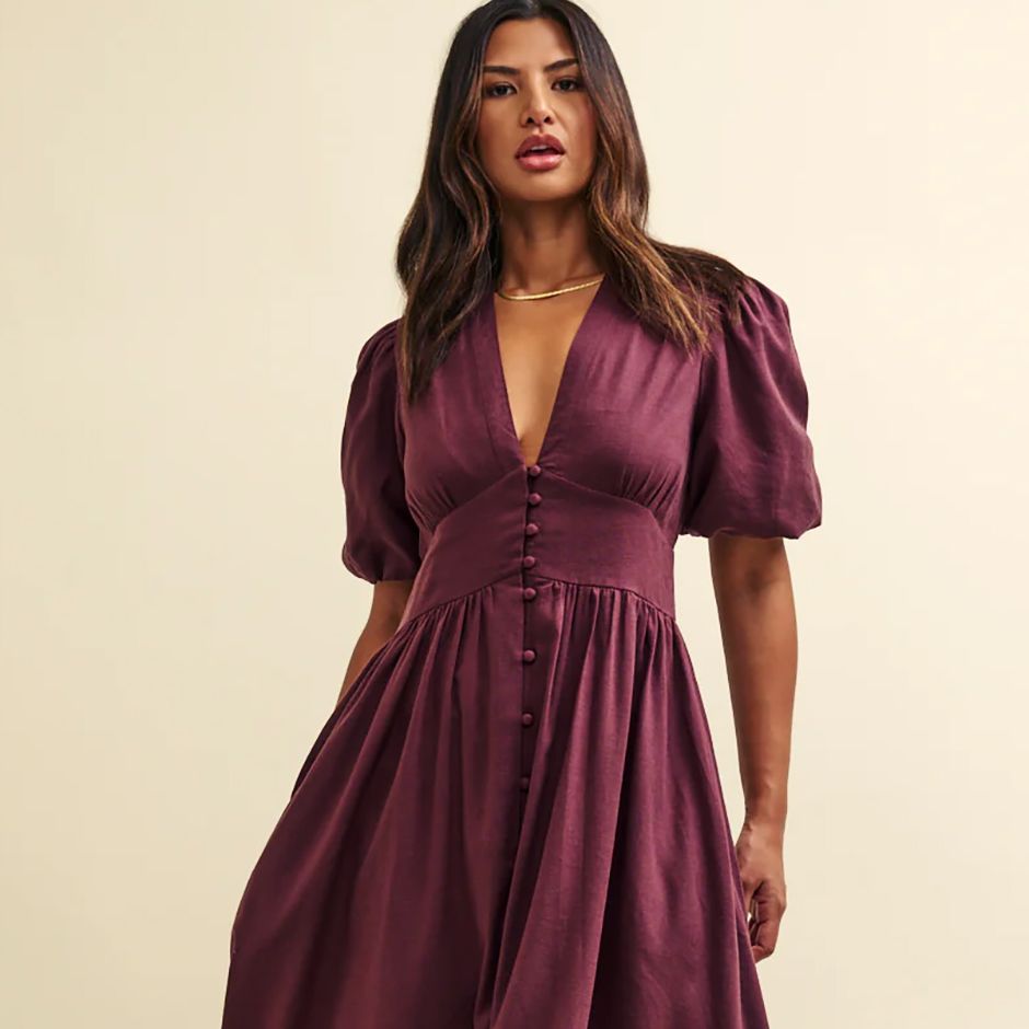 casual wedding guest dress from nobody's child in plum linen, with low v-neck and short puff sleeves.