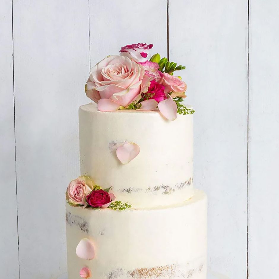 two tier semi-naked wedding cake with pink flower decorations