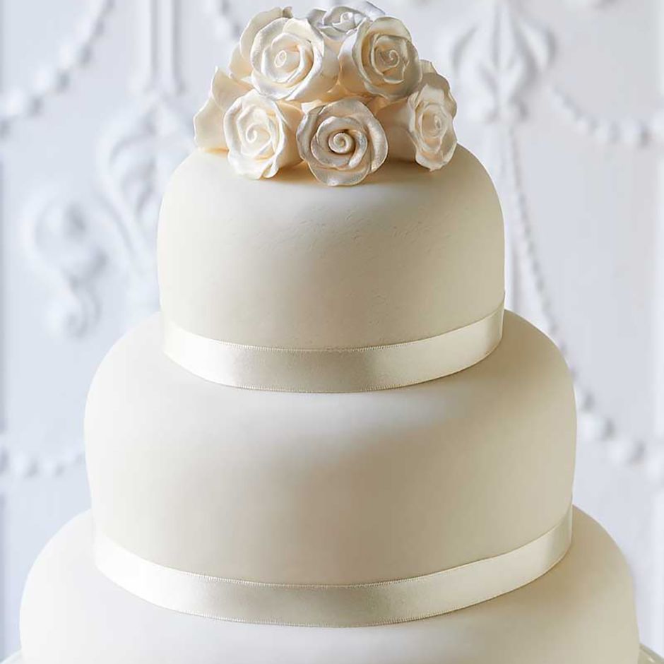 classic white three tier wedding cake for at-home decoration with roses on the top