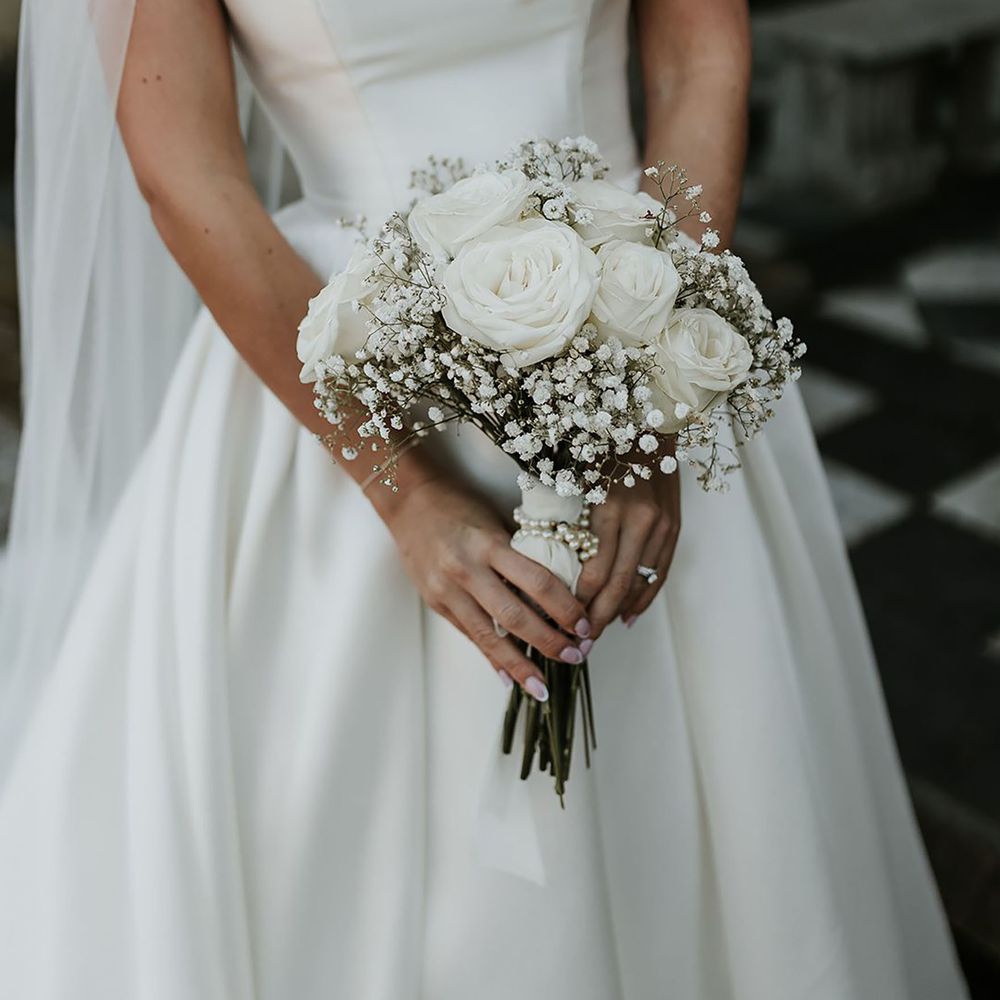 Bride wearing white wedding dress, holding white bouquet