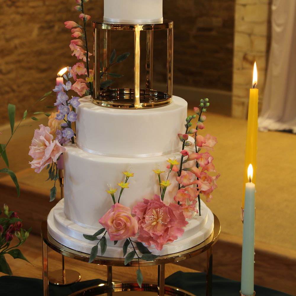 Sugar wildflowers decorated tiered white iced wedding cake with metallic spacer