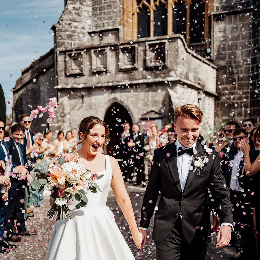 bride-and-groom-walking-together-at-church-wedding-with-pink-confetti