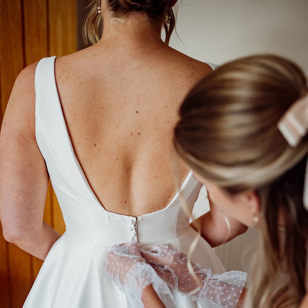 bridesmaid-helps-bride-get-ready-for-wedding