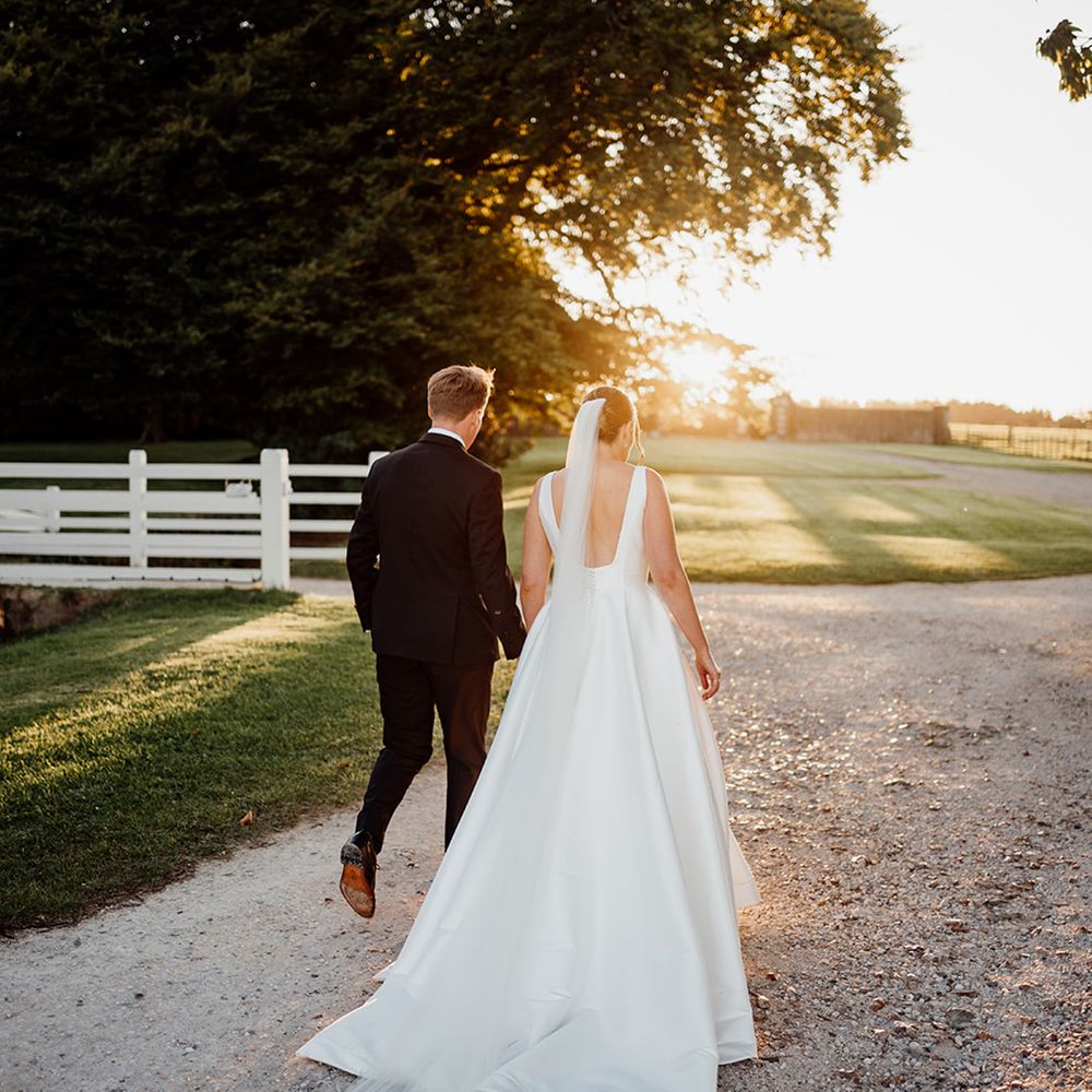 golden-hour-wedding-photo-with-bride-and-groom-walking-towards-the-sunset