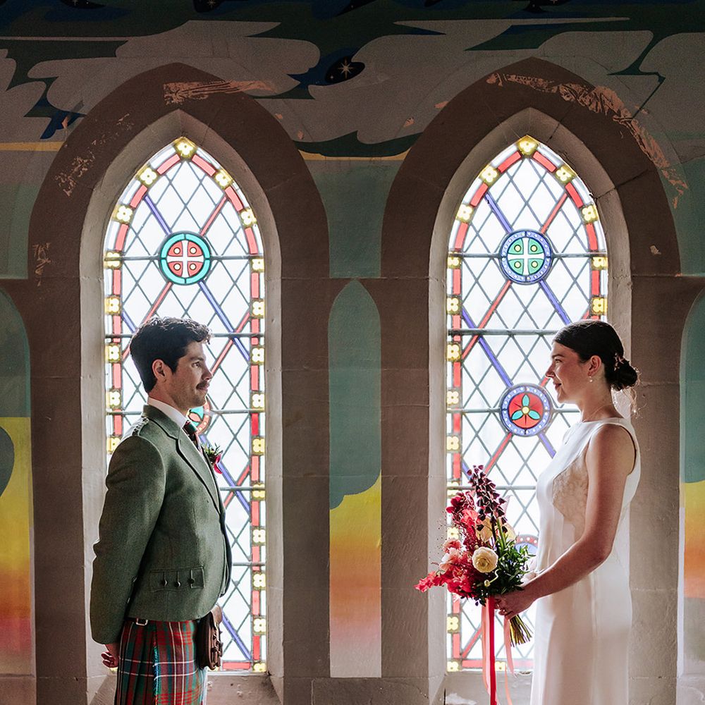 couple-stands-in-front-of-stained-glass-windows
