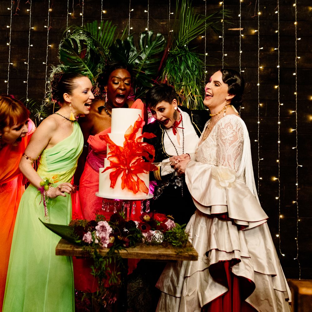 bridal-party-surrounds-white-wedding-cake