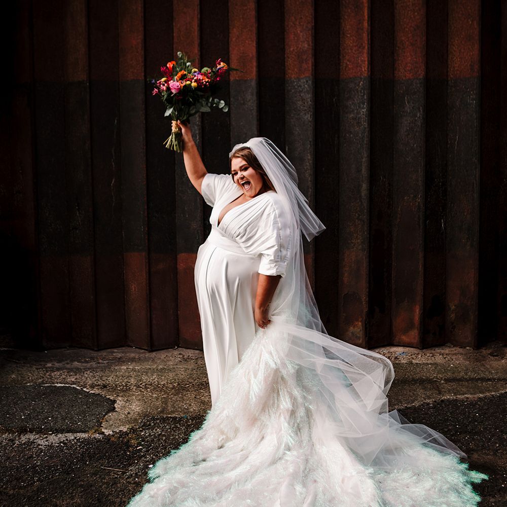 bride-holds-bouquet-in-air-wearing-holographic-tassel-wedding-dress
