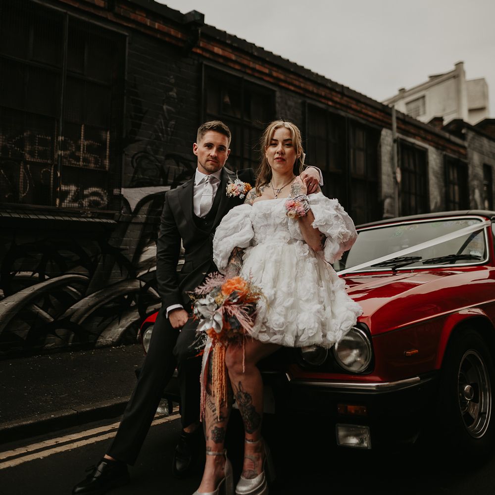 bride-in-short-wedding-dress-with-groom-against-red-wedding-car