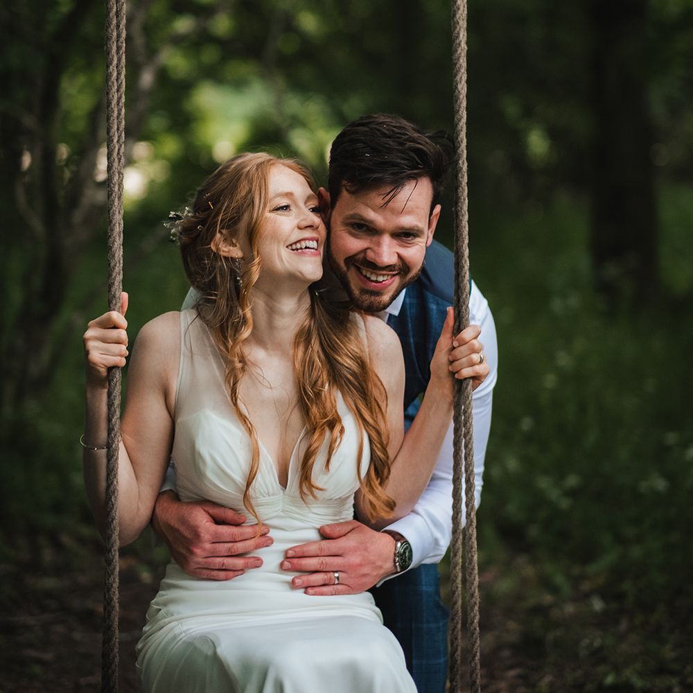 groom-embraces-bride-on-wooden-swing