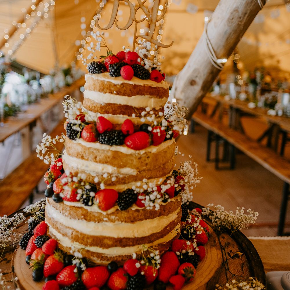 naked-wedding-cake-decorated-with-summer-berries-and-custom-cake-topper