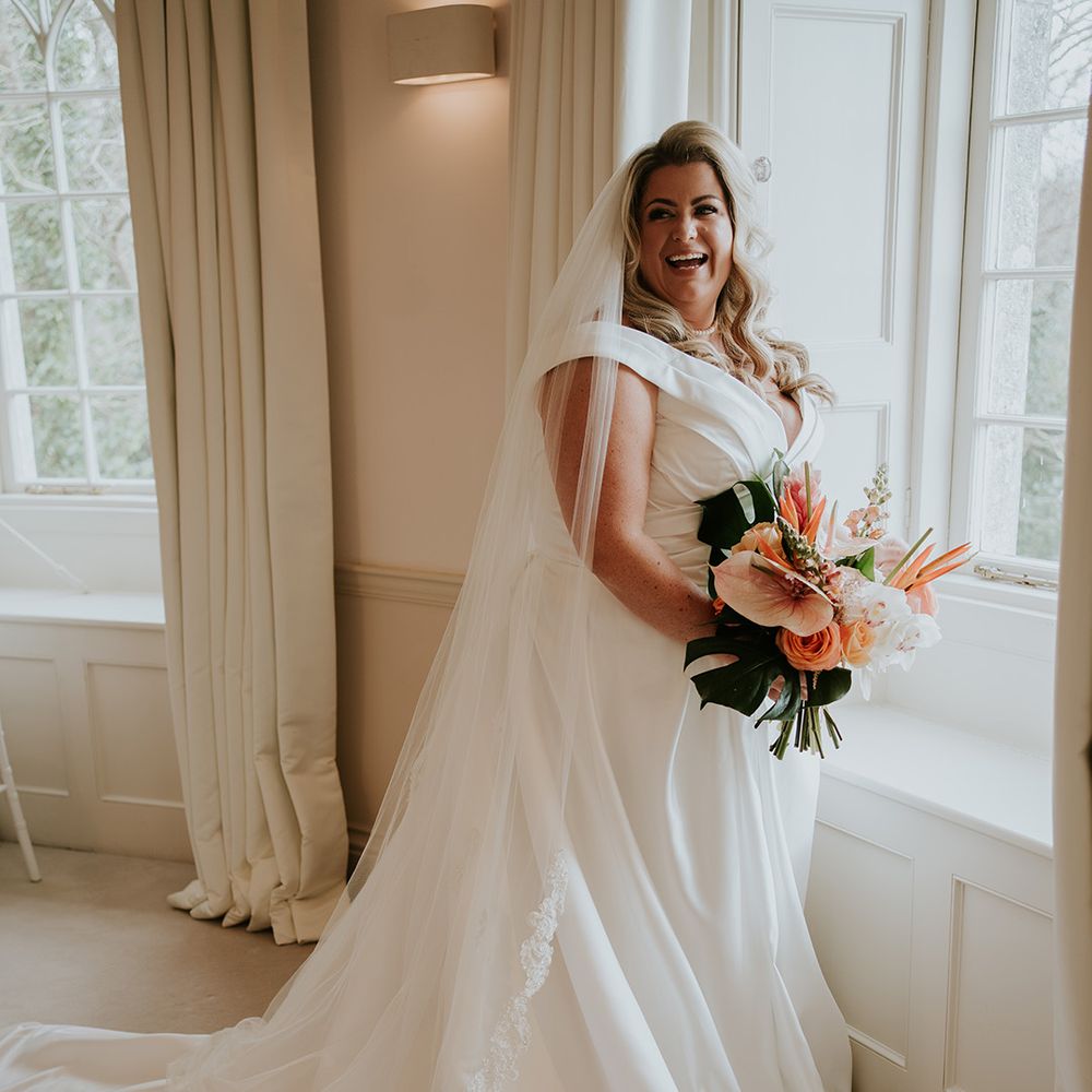 bride-wearing-wedding-dress-with-train-holding-tropical-wedding-bouquet