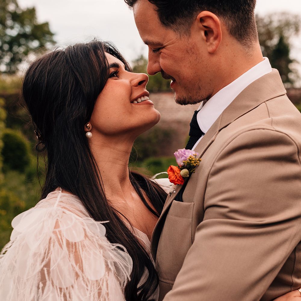 bride-wearing-feather-wedding-dress-smiles-up-at-groom