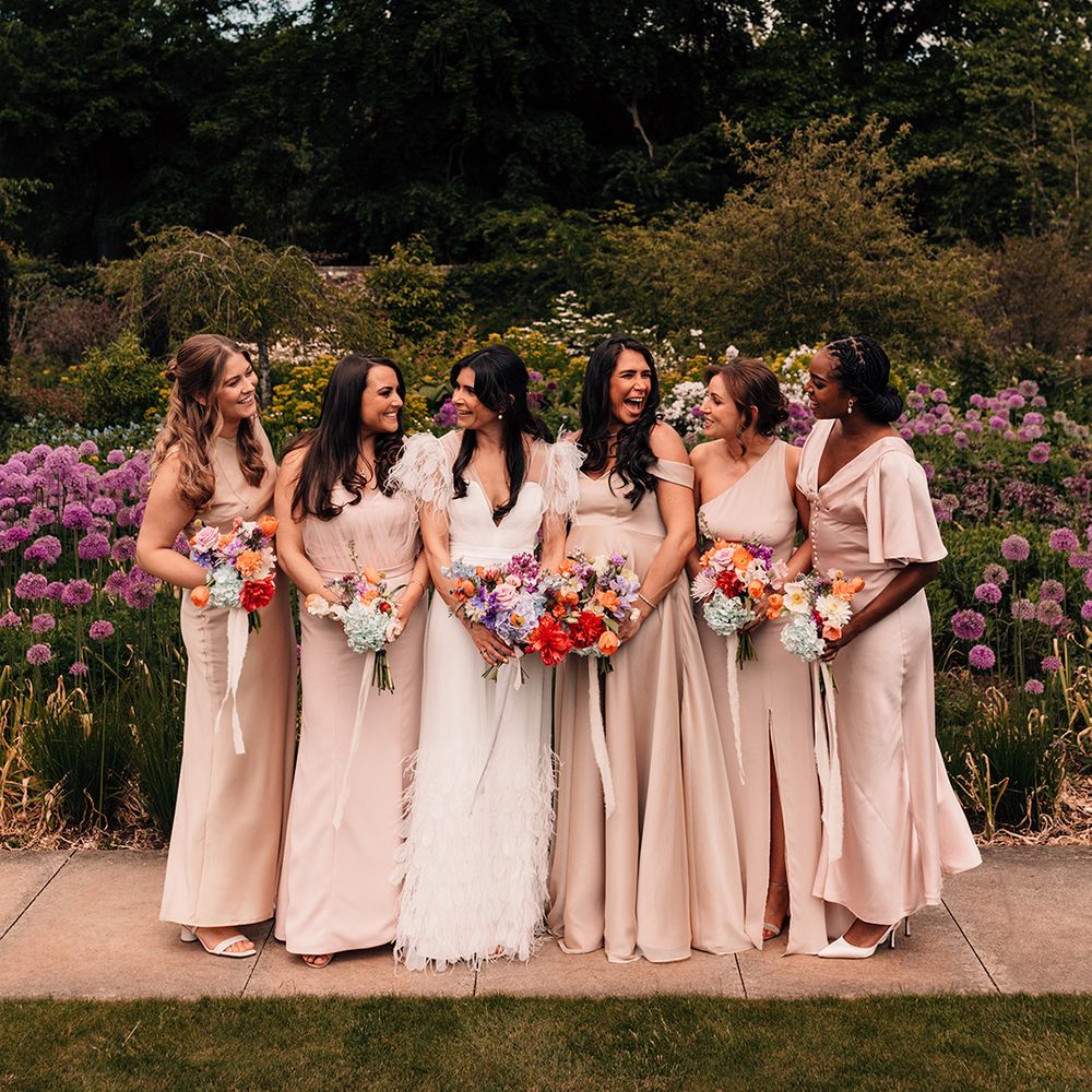bridesmaids-in-neutral-champagne-bridesmaid-dresses-smiling-at-bride-for-group-photo