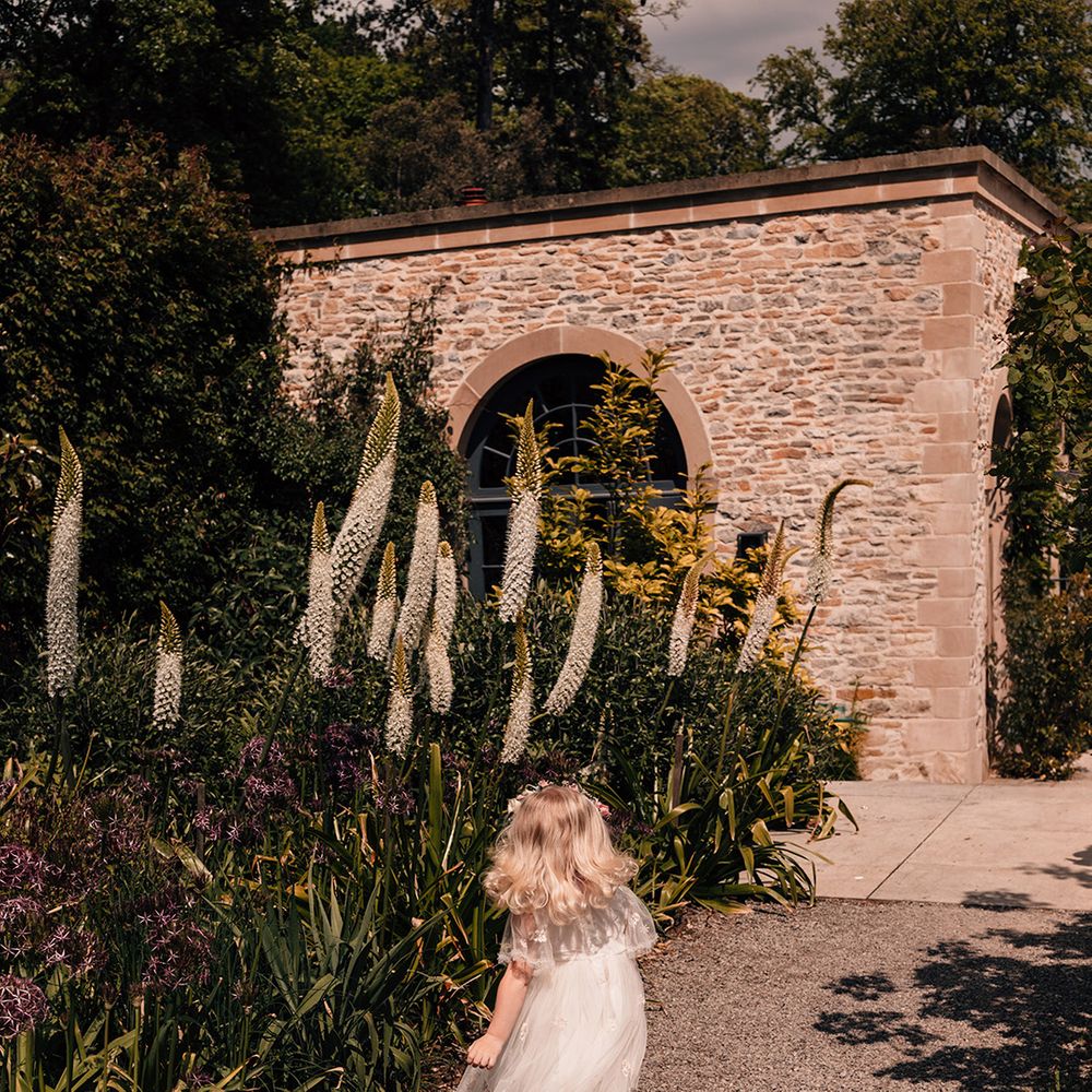 flower-girl-in-white-dress-walking-down-path