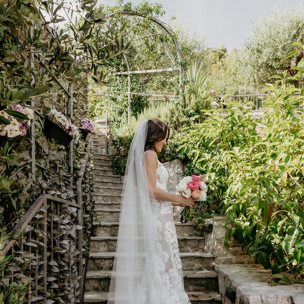 bride-wearing-floral-wedding-dress-with-veil-carrying-bouquet