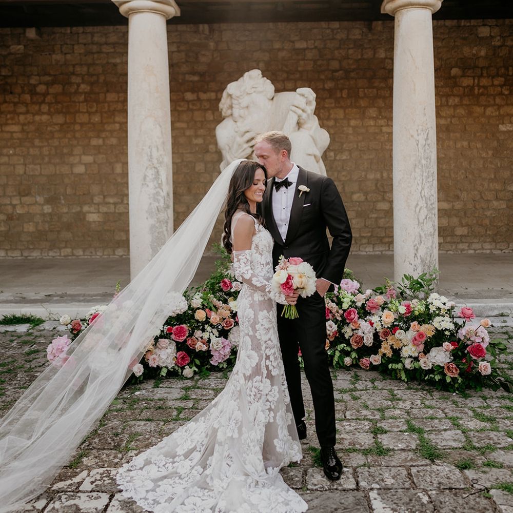 outdoor-wedding-ceremony-space-with-colourful-flowers-as-groom-kissses-the-bride