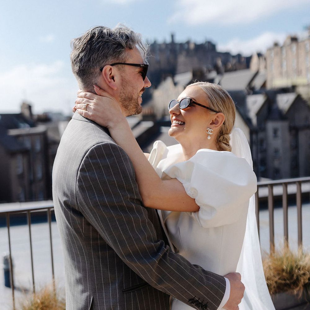 bride-in-puff-sleeve-wedding-dress-embraces-groom-in-grey-suit-with-sunglasses