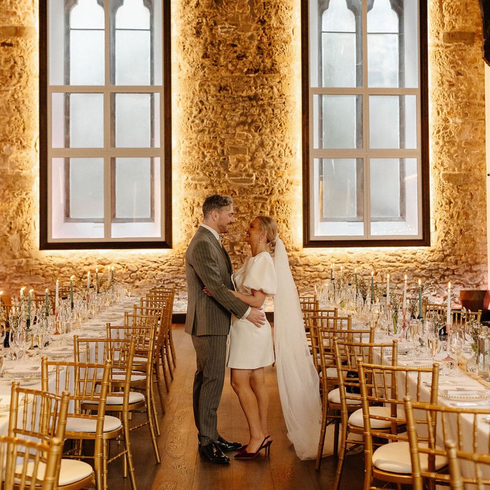 bride-in-short-wedding-dress-and-groom-in-grey-suit-at-hotel-wedding-breakfast