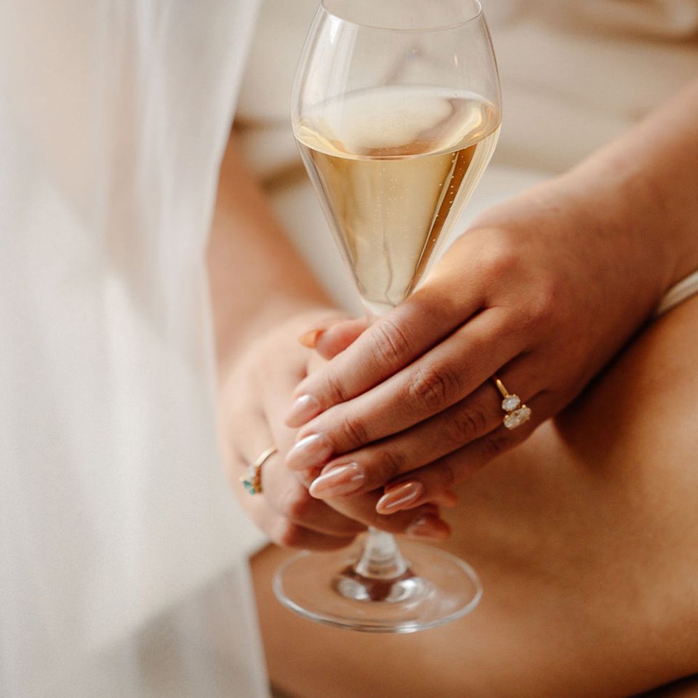 bride-with-pink-almond-chrome-wedding-nails-holds-glass-of-champagne