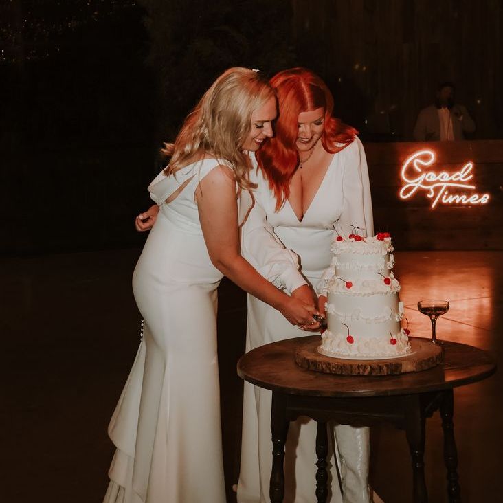 'Good Times' Neon Wedding Sign Backdrop as Two Brides Cut Their Heart Shaped Retro Wedding Cake