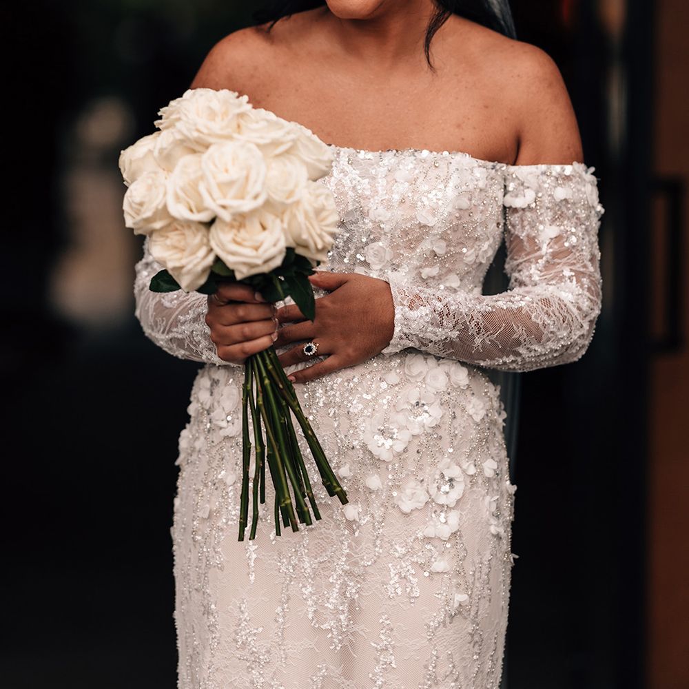 bride-in-off-the-shoulder-wedding-dress-holding-white-rose-wedding-bouquet