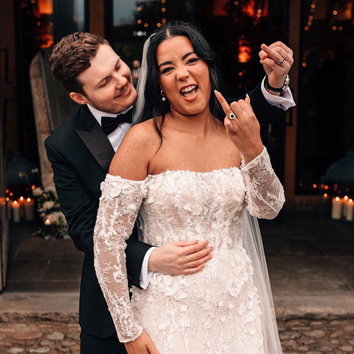 bride-wearing-corset-wedding-dress-with-long-sleeves-and-groom-in-black-tux