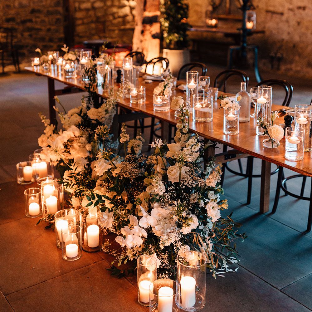 top-table-at-wedding-with-candles-in-hurricane-vases-and-white-flowers
