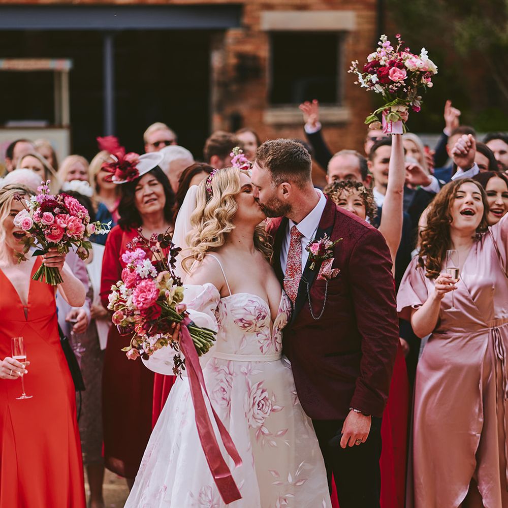 bride-and-groom-kiss-as-wedding-guests-cheer