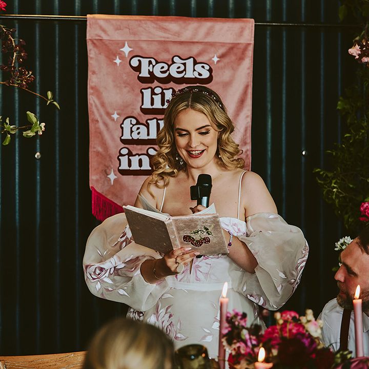 bride-reads-wedding-speech-with-pink-retro-wedding-sign