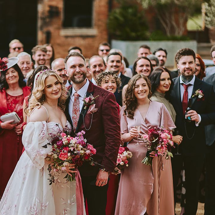 pink-and-red-wedding-dress-code-with-couple-posing-with-guests